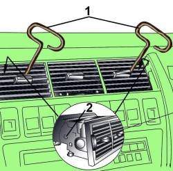 Использование приспособления из проволоки (1), установленного в отверстия (2) для снятия вентиляционной решетки с центральной секции панели приборов