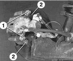 Болты (1) крепления направляющих пальцев и болты (2) крепления направляющей тормозных колодок к оси ступицы колеса